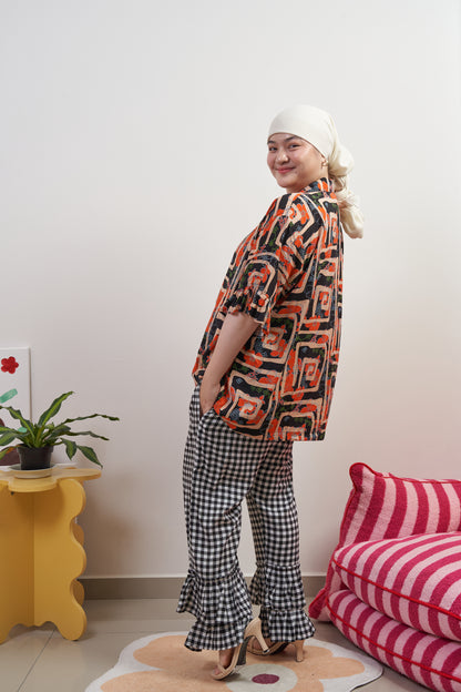 Back-side profile of Buttoned Belle Blouse in Abstract Garden, full-body view paired with Flutter Flair Pants in Noir Blanc, showing abstract print, loose fit, and ruffled sleeves