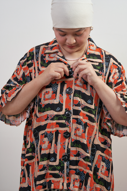 Semi-close-up of Buttoned Belle Blouse in Abstract Garden, model buttoning up to highlight vintage statement buttons and abstract print.