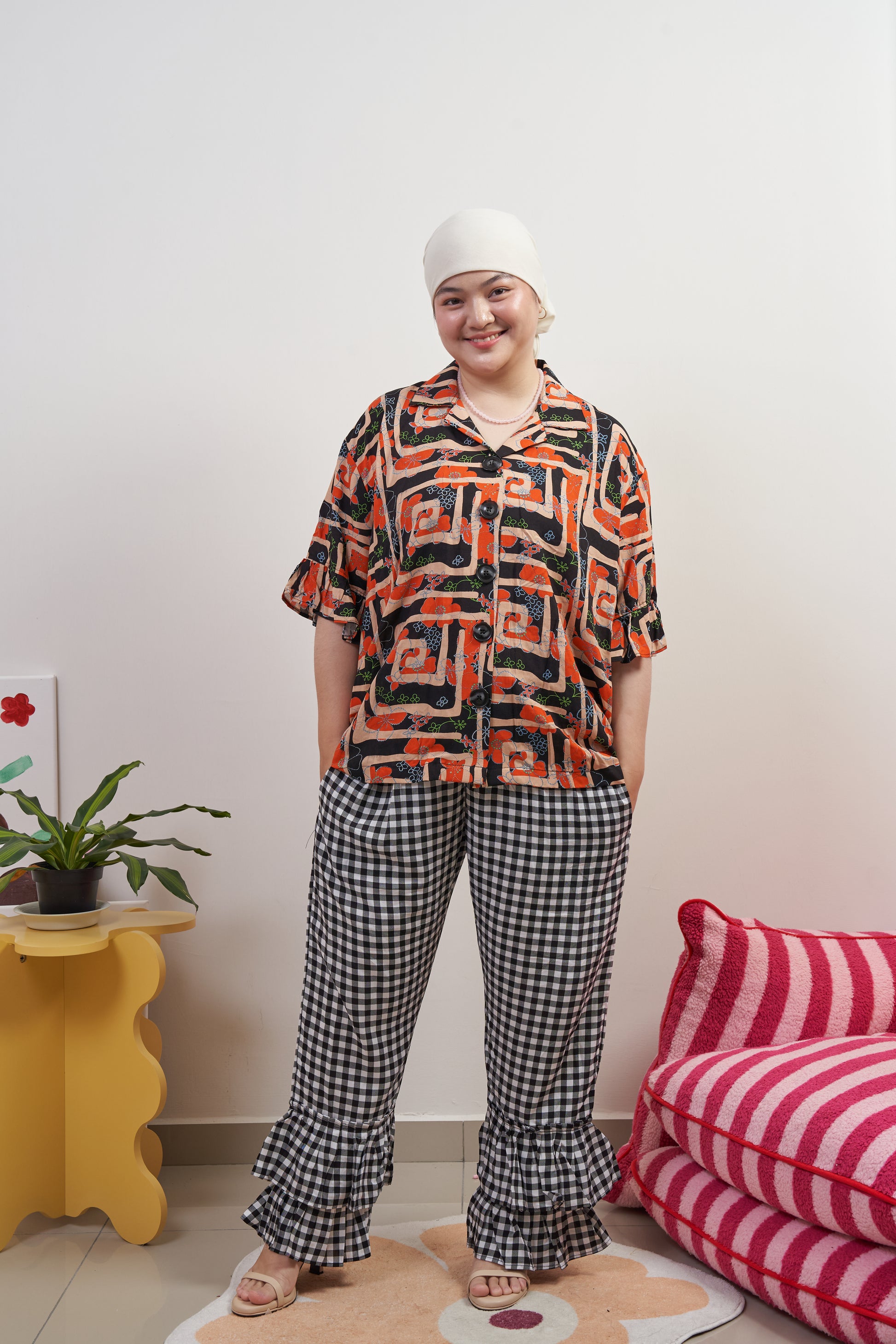 Full frontal view of Buttoned Belle Blouse in Abstract Garden, model with hands in pockets of Flutter Flair Pants in Noir Blanc, showing abstract print and vintage buttons.