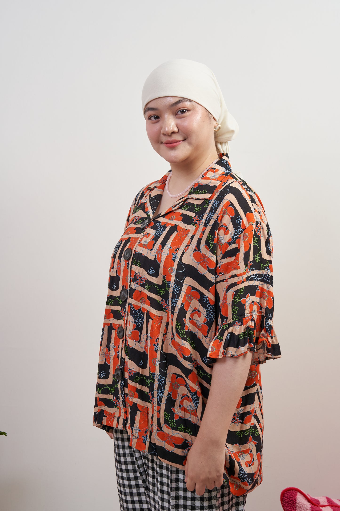 Side-frontal view of Buttoned Belle Blouse in Abstract Garden, paired with Flutter Flair Pants in Noir Blanc, showcasing abstract print, vintage buttons, and ruffled sleeves